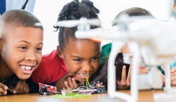 Excited elementary students watch drone in technology class